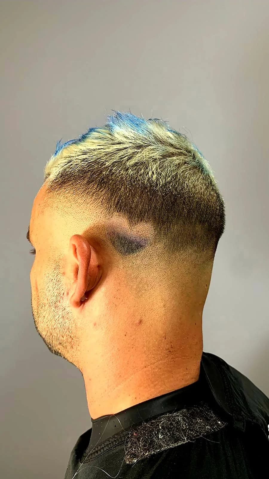 Coupe d'homme vue de trois quarts dos : dégradé très court sur les côtés, dessus décoloré aux pointes bleues