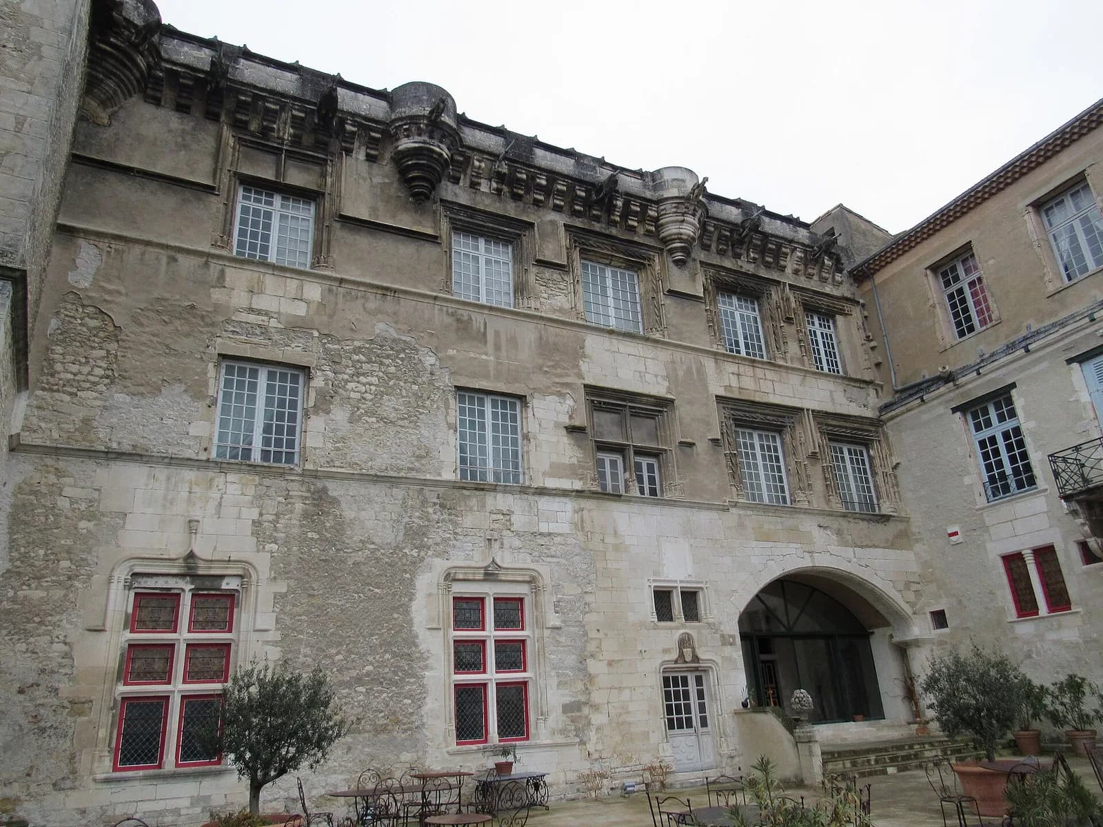 Façade du palais des Évêques côté cour : fenêtres à meneaux, corniche sculptée et porche voûté