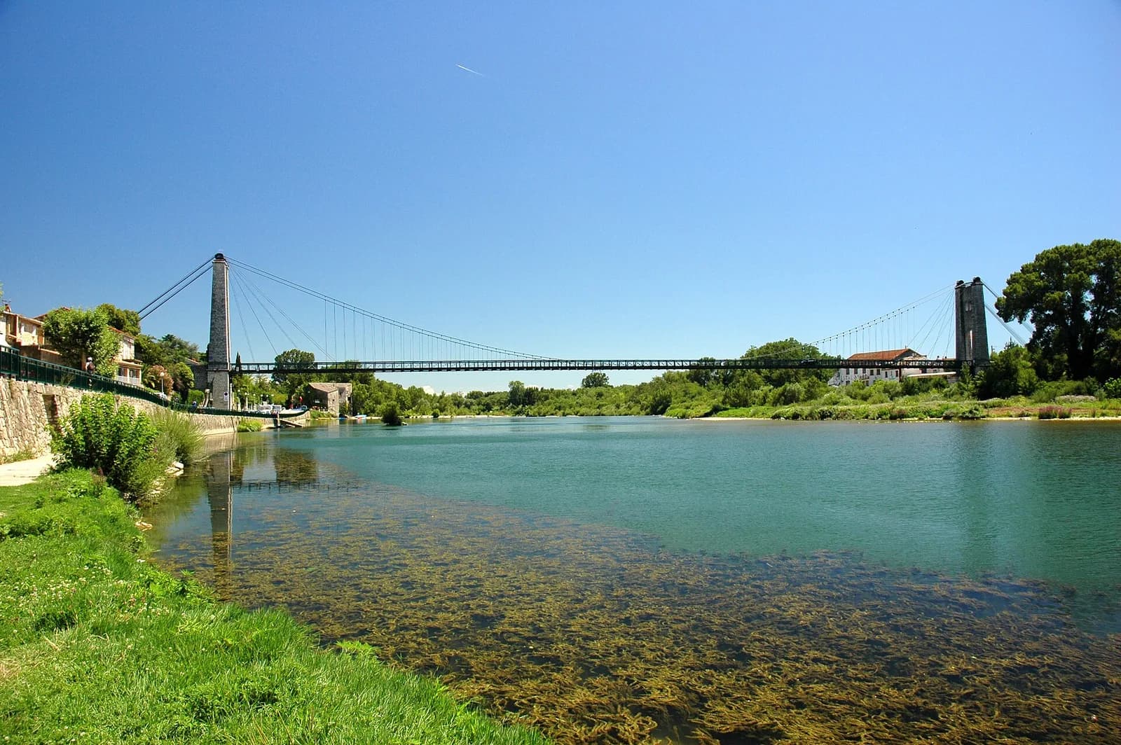 L'Ardèche à Saint-Martin-d'Ardèche : eau verte et claire, berge herbeuse et pont suspendu à l'arrière-plan