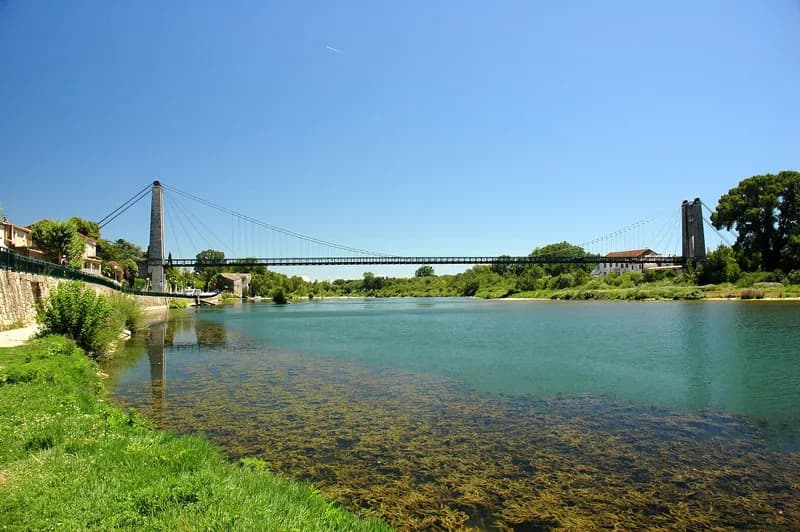 L'Ardèche à Saint-Martin-d'Ardèche : eau verte et claire, berge herbeuse et pont suspendu à l'arrière-plan
